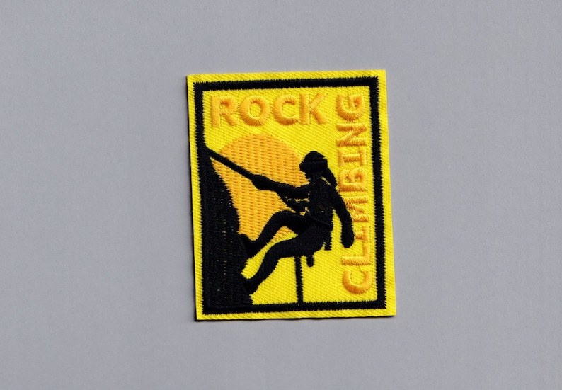 May include: Yellow embroidered patch with a black silhouette of a person rock climbing. The patch says "ROCK CLIMBING" in yellow thread.