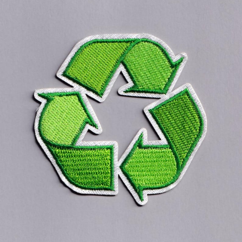 May include: Embroidered green recycling symbol patch with a white border. The patch features the classic three-arrow design, representing the concept of reduce, reuse, and recycle. The patch is on a gray background.