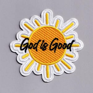 May include: Embroidered patch in the shape of a daisy with a yellow center and white petals. The patch features the phrase "God is Good" in black script, adding a positive message to the design. The patch is suitable for clothing or accessories.