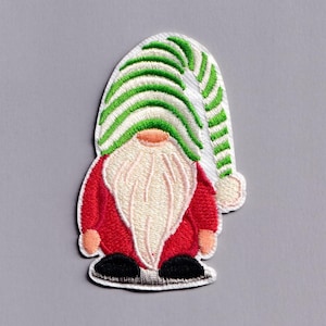 May include: Embroidered patch featuring a Christmas gnome. The gnome wears a red coat, a long white beard, and a green and white striped hat. The gnome's shoes are black, set against a grey background.