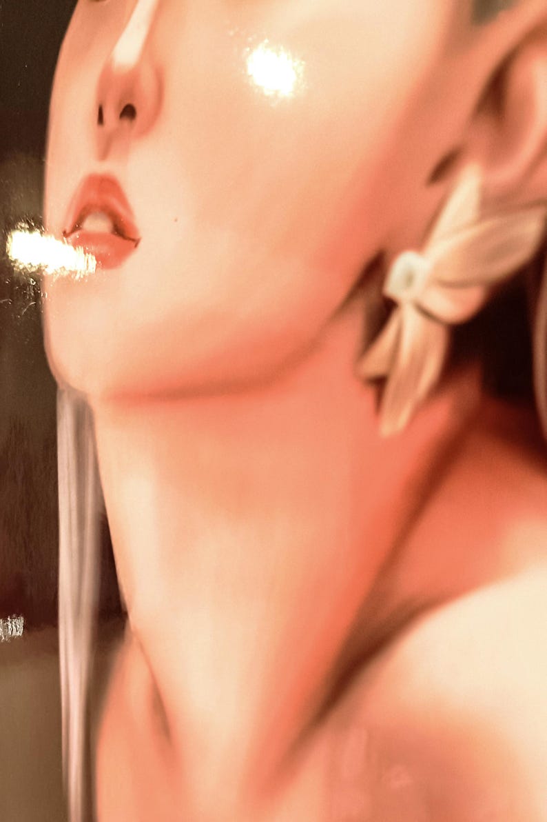 May include: A close-up of a person's face, with a focus on the lips and a wisp of smoke. The skin has a warm, peachy tone, and the lips are a vibrant red. A white, flower-shaped earring is visible. The image has a soft, artistic quality.