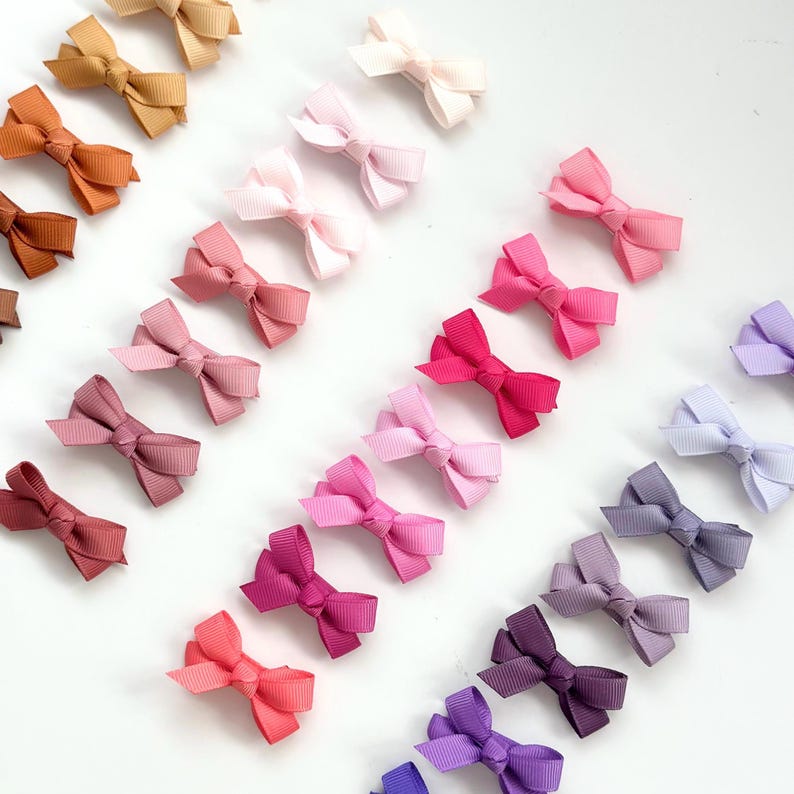 Puede incluir: Un conjunto de 20 mini lazos para el pelo en un degradado de colores, que van del marr&oacute;n al morado. Los lazos est&aacute;n hechos de cinta de sat&eacute;n y est&aacute;n unidos a pinzas de cocodrilo.