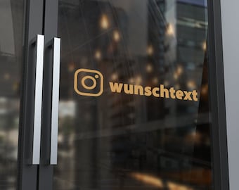 Puede incluir: Un icono del logotipo de Instagram de color dorado y el texto "wunschtext" aplicados como calcomanía en una puerta de cristal con un marco gris oscuro. El diseño está colocado horizontalmente sobre la superficie transparente.