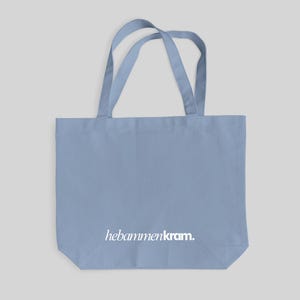 May include: A light blue tote bag with two shoulder straps and the white text hebammenkram. printed in a lowercase serif font on the lower front section. The bag features a rectangular body with a flat base and a simple, functional design.