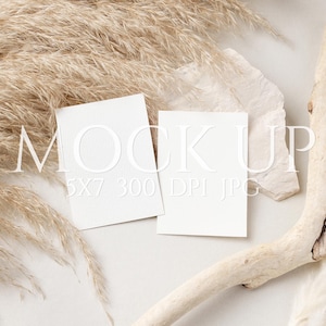 Puede incluir: Maqueta de producto con dos tarjetas blancas en blanco, la palabra "MOCK UP" y otro texto. Las tarjetas están rodeadas de hierba de la pampa beige, madera flotante y piedra blanca sobre un fondo blanco. Tema minimalista y neutro.