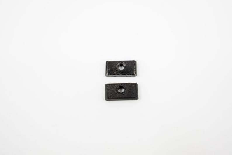 May include: Two black plastic rectangular blocks with a hole in the center.