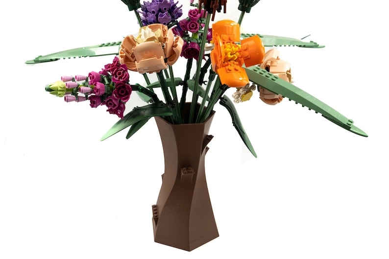 Peut inclure: Un vase en c&eacute;ramique brun avec un design en spirale unique contient un bouquet de fleurs Lego color&eacute;es. Les fleurs comprennent des fleurs roses, violettes, orange et jaunes.