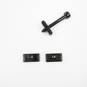 May include: A set of three black plastic hardware pieces, including a screw with a head and two rectangular plates with holes.