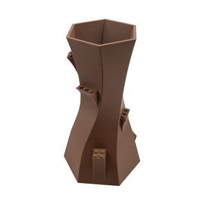 Peut inclure: Un vase en c&eacute;ramique brun avec un design unique et torsad&eacute;. Le vase a une ouverture hexagonale en haut et une base large.