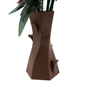 Peut inclure: Un vase en c&eacute;ramique brun avec un design unique et torsad&eacute;. Le vase a une large ouverture en haut et une base &eacute;troite. Il pr&eacute;sente plusieurs petites saillies d&eacute;coratives sur les c&ocirc;t&eacute;s.