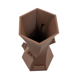 Peut inclure: Un vase en c&eacute;ramique brun avec un design g&eacute;om&eacute;trique unique. Le vase a une ouverture hexagonale et une forme torsad&eacute;e en sablier.
