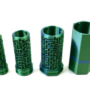 May include: Four green cylindrical containers. Three have a maze-like design, and one holds a rolled-up bill. The fourth container is a solid green, hexagonal shape. All are made of a shiny, textured material.