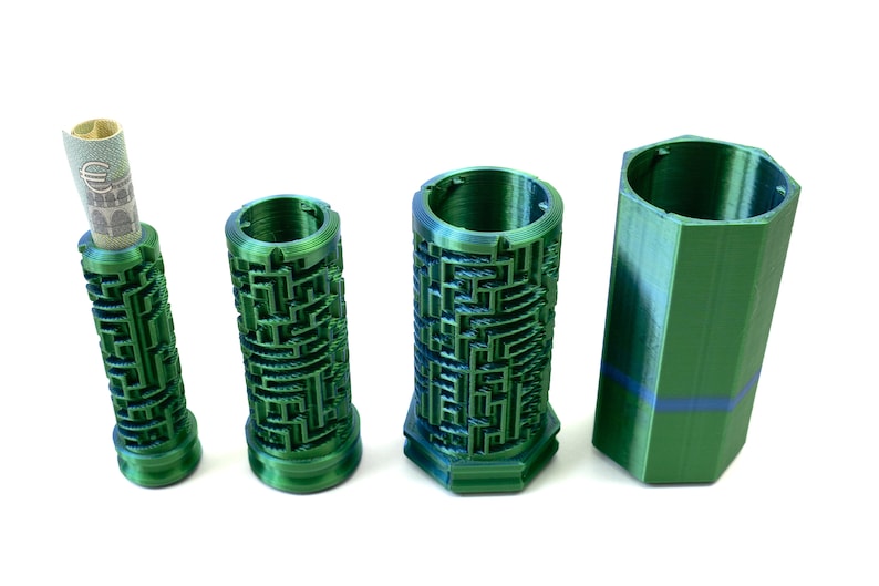 May include: Four green cylindrical containers. Three have a maze-like design, and one holds a rolled-up bill. The fourth container is a solid green, hexagonal shape. All are made of a shiny, textured material.