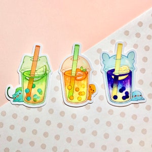 May include: Three colorful bubble tea stickers. One is green with a lime slice, another is orange with a strawberry, and the last is purple with a lemon slice. Each has a straw and a cute character.