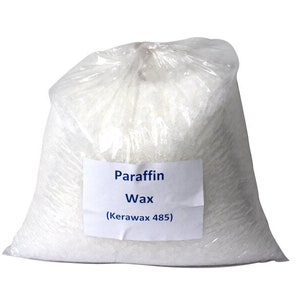 May include: A white plastic bag filled with white paraffin wax flakes. The bag has a label that reads "Paraffin Wax (Kerawax 485)".
