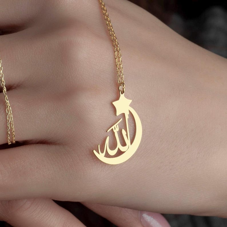 A gold necklace with a crescent moon and star pendant. The pendant features the Arabic word for 'Allah' inside the crescent moon.Allah Necklace can be worn every day. It is made by hand in our workshop with care. All our jewelry is the most elegant choice for the bridesmaids, friends, your loved ones and for yourself. It is also a fact that silver jewelry improves blood circulation and provides electricity and makes you feel awake.