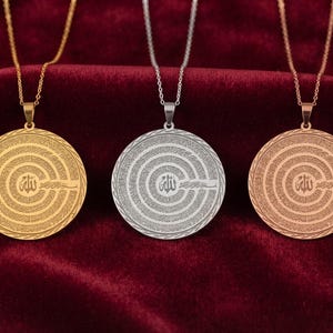 Pu&ograve; includere: Tre ciondoli circolari su sottili catene di metallo, presentati in tonalit&agrave; oro, argento e oro rosa. Ogni ciondolo presenta un simbolo calligrafico arabo centrale circondato da cerchi concentrici di intricati motivi testuali incisi.