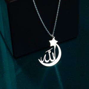 Peut inclure: Un collier de couleur argent&eacute;e avec un pendentif en forme de croissant de lune et d'&eacute;toile. Le croissant de lune contient la calligraphie arabe pour Allah. Le pendentif est suspendu &agrave; une d&eacute;licate cha&icirc;ne &agrave; maillons argent&eacute;e.