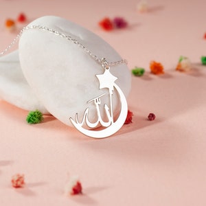 Peut inclure: Un collier argent&eacute; avec un pendentif en forme de croissant de lune et d'&eacute;toile. Le centre du croissant de lune affiche la calligraphie arabe pour Allah. Le pendentif est attach&eacute; &agrave; une d&eacute;licate cha&icirc;ne de collier &agrave; maillons argent&eacute;s.