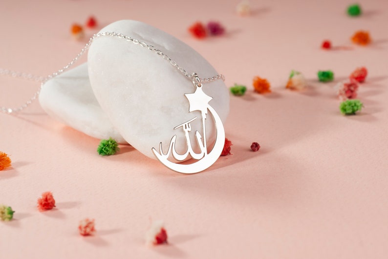 Peut inclure: Un collier argent&eacute; avec un pendentif en forme de croissant de lune et d'&eacute;toile. Le centre du croissant de lune affiche la calligraphie arabe pour Allah. Le pendentif est attach&eacute; &agrave; une d&eacute;licate cha&icirc;ne de collier &agrave; maillons argent&eacute;s.