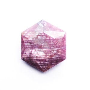 May include: A pink and white hexagonal gemstone with a striated pattern.