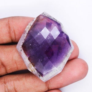Pu&ograve; includere: Un grande gioiello di ametista sfaccettato con una tonalit&agrave; viola e un bordo bianco nuvoloso. Il gioiello &egrave; tagliato in una forma geometrica unica.