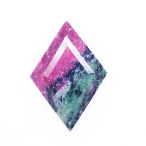 May include: A faceted gemstone with a pink, green, and blue color pattern. The gemstone is cut in a diamond shape.
