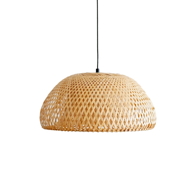 May include: A woven bamboo pendant light fixture. The light has a dome-shaped shade with a diamond pattern. The light hangs from a black cord against a white background. The shade is a light tan color.