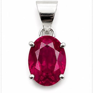 May include: An oval-cut, deep red gemstone pendant set in a polished silver-toned metal prong setting. The faceted stone features a brilliant, reflective surface, secured by four small prongs and attached to a silver-toned metal bail at the top.