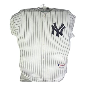 May include: White and navy blue pinstripe baseball jersey with the New York Yankees logo on the chest. The jersey has short sleeves, a button-up front, and the Majestic brand label.