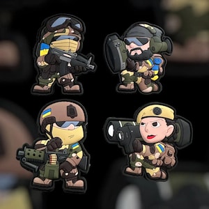 May include: Four cartoon-style patches featuring soldiers in camouflage uniforms. Each patch depicts a soldier with different weapons and gear, including rifles, shields, and rocket launchers. The patches incorporate the colors of the Ukrainian flag.