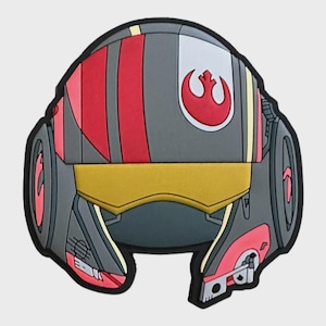 Pode incluir: Um acessório cinza, vermelho e amarelo em forma de capacete com um símbolo vermelho. O acessório tem uma forma arredondada com uma faixa amarela no centro e listras vermelhas na parte superior. O design inclui um símbolo vermelho sobre um fundo branco.