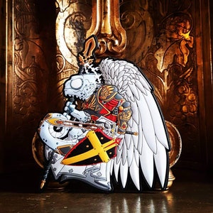 May include: A white and gold detailed patch of a winged, armoured figure holding a sword and shield. The figure is wearing a red and gold suit of armour and has a white helmet with a gold crest. The shield is black with a yellow cross.