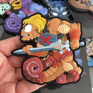 May include: A brown and red cartoon character with a sword, wearing a red and white chest plate with a cross on it. The character is riding a brown and pink snake.