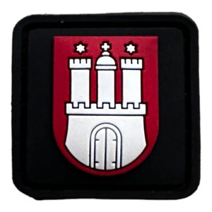 May include: A square, black patch displaying the Hamburg coat of arms. The emblem features a red shield with a white castle and three towers, topped with three six-pointed stars. The castle has a silver base.
