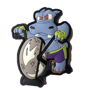 May include: A blue hippopotamus cartoon character wearing a purple and green outfit is riding an exercise bike. The bike has a gray wheel with white markings.