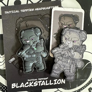 Op de afbeelding: Zwarte en grijze geborduurde patch van een cartoonbeer met een tactische helm en een geweer. De patch heeft de tekst "Tactical Teddies" en "Blackstallion".