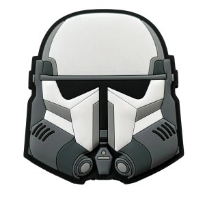 May include: A black and white 3D printed patch of a Star Wars Stormtrooper helmet. The helmet is white with black details and a gray visor.