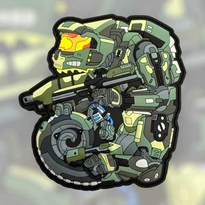 May include: A detailed patch featuring a green and yellow armored figure holding a rifle. The design has a black border and a complex, layered appearance. The figure's helmet has a yellow visor.