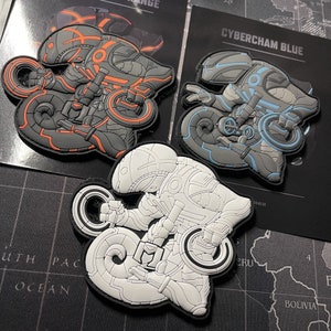 May include: Three embroidered patches featuring a futuristic robot design. The patches are in black, white, and blue with the text "Cybercham Blue".