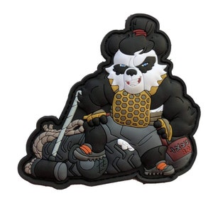 May include: A black, white, and tan panda bear patch in a sumo wrestler pose. The panda wears a gold and brown chest plate, gray shorts, and orange shoes. It holds a sword and sits atop a gray and tan object.