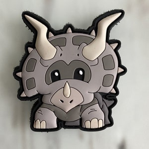 May include: A gray, cartoon-style, three-horned dinosaur with big eyes and a small mouth. The dinosaur is standing on its two back legs and has a small tail.