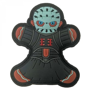 May include: A black and red rubber patch of a cartoon gingerbread man with a hockey mask and a red and black striped shirt.