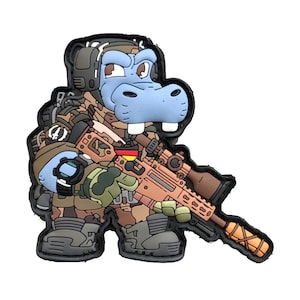 Puede incluir: Un parche de dibujos animados con un hipopótamo con uniforme militar, sosteniendo un rifle. El hipopótamo es azul claro con un uniforme de camuflaje y un contorno negro. El rifle tiene una mira y la bandera alemana es visible.