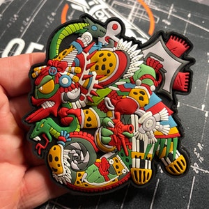 Könnte beinhalten: Ein farbenfroher, mehrschichtiger und detaillierter Patch mit einer mythischen Kreatur in Rot, Grün und Gelb. Der Patch ist aus strapazierfähigem Material gefertigt und hat eine strukturierte Oberfläche.