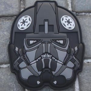 Pode incluir: Uma placa de madeira rústica com o texto "Welcome to our home" em letras brancas. A placa apresenta um acabamento desgastado e um design simples e convidativo, perfeito para a decoração da porta da frente.