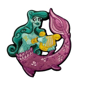 May include: Embroidered patch depicting a teal mermaid playing a golden harp. The mermaid has teal hair and a purple tail. The patch uses shades of teal, purple, and gold, set against a white background. This patch is likely for clothing or accessories, and is suitable for sewing or ironing on.