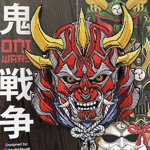 May include: An embroidered patch depicting a Japanese Oni demon mask in red and gold. The mask has a fierce expression with sharp teeth, horns, and intricate details.