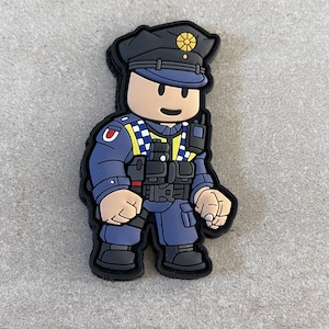 Può includere: Una toppa in stile cartone animato raffigurante un agente di polizia in uniforme blu scuro, cappello nero e giubbotto tattico. La toppa ha un bordo nero e un retro in velcro. L'ufficiale ha una radio e un distintivo sul cappello.