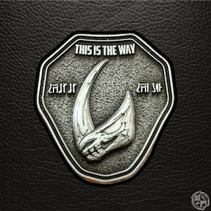 Könnte beinhalten: Eine silberne Metallstifte mit einem mandalorianischen Symbol und dem Text "This is the Way".